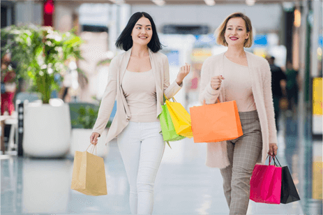 Two happy women with shopping bags walking together.